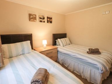 A bedroom with two single beds and a nightstand with a lamp at Horseshoe Lodge Wansfell 5 Limefitt Park near Windermere