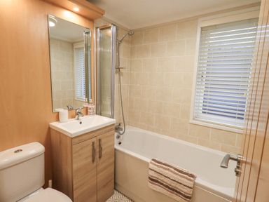 A bathroom with a toilet sink cabinet bathtub and window blinds at Horseshoe Lodge Wansfell 5 Limefitt Park near Windermere