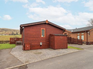 A wooden cabin with a small shed and gravel driveway in a rural area at Horseshoe Lodge Wansfell 5 Limefitt Park near Windermere