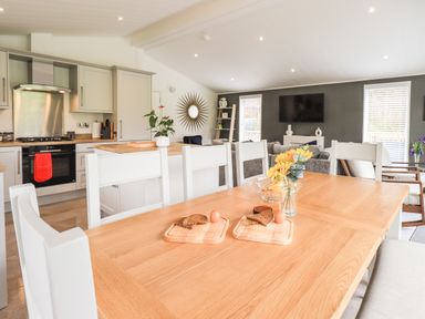 A dining table with bread and eggs in a kitchen and living area at Jinnyspinner Lodge in Beckside 37 Limefitt Park near Windermere