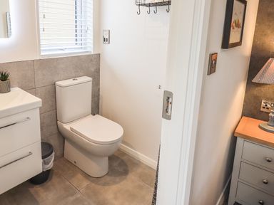 A bathroom with a toilet a sink and a window at Jinnyspinner Lodge Beckside 37 Limefitt Park near Windermere