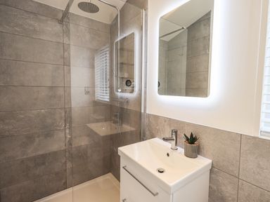 A bathroom with a shower area a sink with a faucet and a lit mirror at Jinnyspinner Lodge Beckside 37 Limefitt Park near Windermere
