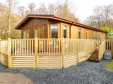 A wooden lodge with a fenced deck and stairs at Langdale Lodge Langdale 21 White Cross Bay near Windermere