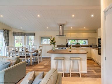 A kitchen with a wooden island and two stools next to a dining table with chairs at Langdale Lodge Langdale 21 White Cross Bay near Windermere