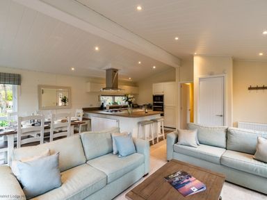 An open plan living room with two sofas a coffee table and a kitchen with a dining table at Langdale Lodge Langdale 21 White Cross Bay near Windermere