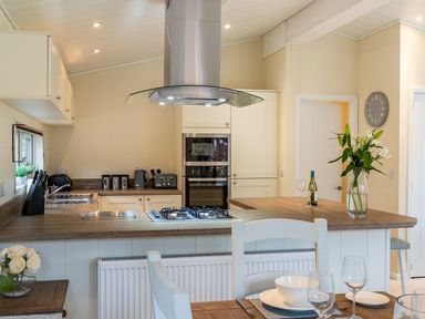 A kitchen with countertop stove oven and dining table with dishes and glasses at Langdale Lodge Langdale 21 White Cross Bay near Windermere