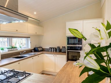A kitchen with white cabinets and wooden countertops with a gas stove and a sink near a window at Langdale Lodge Langdale 21 White Cross Bay near Windermere