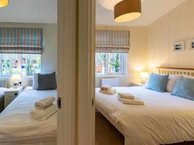 Two bedrooms with beds pillows and folded towels by windows with striped blinds at Langdale Lodge Langdale 21 White Cross Bay near Windermere