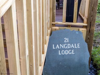 A stone sign with Langdale Lodge 21 beside a wooden railing Langdale Lodge Langdale 21 White Cross Bay near Windermere