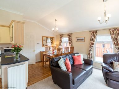 A living room with a black leather sofa and dining table with chairs at Hideaway Lodge Kirkstone 14 Limefitt Park near Windermere