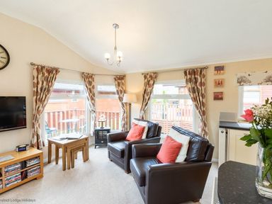 A living room with two leather chairs and patterned curtains at Hideaway Lodge Kirkstone 14 Limefitt Park near Windermere