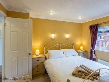 A bedroom with a double bed and bedside tables with lamps at Hideaway Lodge Kirkstone 14 Limefitt Park near Windermere