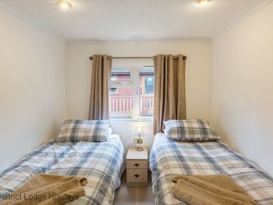 A bedroom with two single beds with plaid bedding and a nightstand between them at Hideaway Lodge Kirkstone 14 Limefitt Park near Windermere