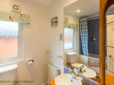 A bathroom with a sink toilet bathtub shower curtain and a window at Hideaway Lodge Kirkstone 14 Limefitt Park near Windermere
