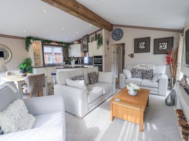A living room with sofas and a coffee table beside a kitchen and dining area at Valley View Lodge in Wansfell 10 Limefitt Park near Windermere