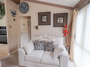 A sitting area with a white sofa and two patterned cushions near decorated wall at Valley View Lodge Wansfell 10 Limefitt Park near Windermere