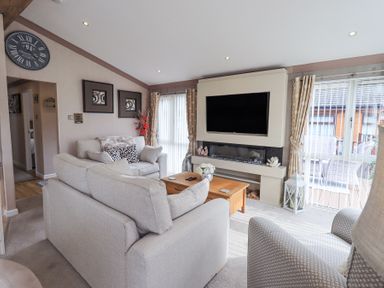 A living room with sofas a coffee table television and fireplace at Valley View Lodge Wansfell 10 Limefitt Park near Windermere