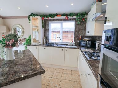 A kitchen with brown countertops white cabinets a sink and a stove at Valley View Lodge Wansfell 10 Limefitt Park near Windermere