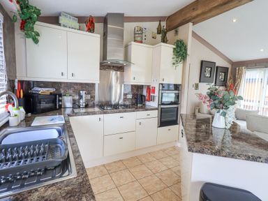 A kitchen with cream cabinets brown countertops and a sink with drying rack at Valley View Lodge Wansfell 10 Limefitt Park near Windermere
