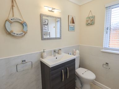 A bathroom with a sink in a cabinet a toilet a mirror and nautical themed decorations at Valley View Lodge Wansfell 10 Limefitt Park near Windermere