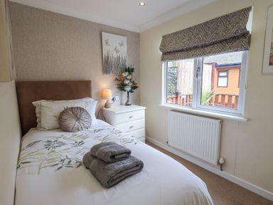 A small bedroom with a single bed bedside table lamp and window at Valley View Lodge Wansfell 10 Limefitt Park near Windermere