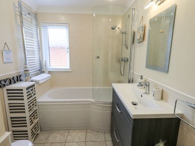 A bathroom with a bathtub shower combination a sink with cabinet and a window at Valley View Lodge Wansfell 10 Limefitt Park near Windermere