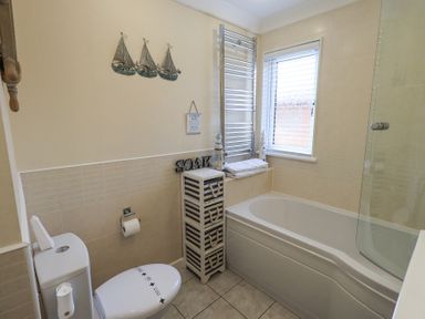 A bathroom with a toilet a bathtub a small cabinet towels and wall decorations at Valley View Lodge in Wansfell 10 Limefitt Park near Windermere