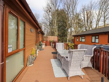 A wooden deck with wicker chairs and a table at Valley View Lodge in Wansfell 10 Limefitt Park near Windermere