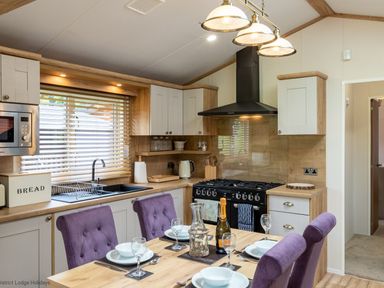 A kitchen with a dining table set with dishes and glasses and purple chairs at Latterbarrow Lodge in Beckside 46 Limefitt Park near Windermere