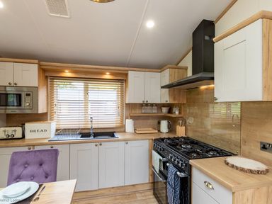 A kitchen with a stove oven microwave toaster sink cabinets and a purple chair at Latterbarrow Lodge Beckside 46 Limefitt Park near Windermere