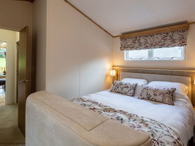 A bedroom with a bed two pillows and a window with floral blinds at Latterbarrow Lodge in Beckside 46 Limefitt Park near Windermere