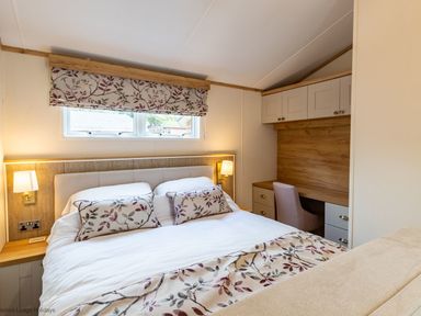A bedroom with a double bed a desk with chair and overhead cabinets at Latterbarrow Lodge in Beckside 46 Limefitt Park near Windermere