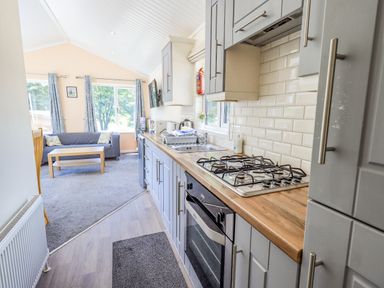 A kitchen with gray cabinets and a wooden countertop connected to a living area with a sofa and coffee table at Robin View Lodge Beckside 3 Limefitt Park near Windermere