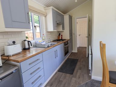 A kitchen with blue cabinets wooden countertop white toaster kettle and sink at Robin View Lodge Beckside 3 Limefitt Park near Windermere