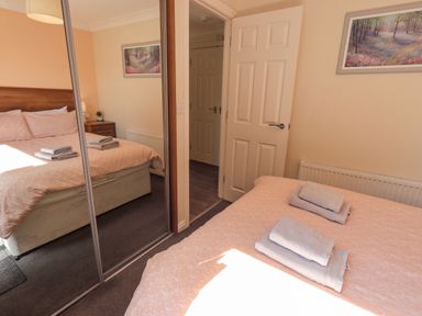 A bedroom with a double bed covered with towels a bedside table with a lamp and a mirrored wardrobe at Robin View Lodge Beckside 3 Limefitt Park near Windermere