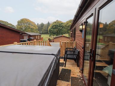 An outdoor area with a hot tub and chairs at Robin View Lodge, Beckside 3, Limefitt Park near Windermere