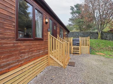 An exterior view of a wooden lodge with steps and gravel area at Robin View Lodge Beckside 3 Limefitt Park near Windermere
