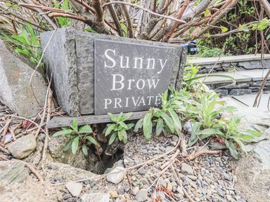 A stone plaque with the words Sunny Brow Private surrounded by plants and rocks at Sunny Brow Lodge Lakeside 5 White Cross Bay near Windermere