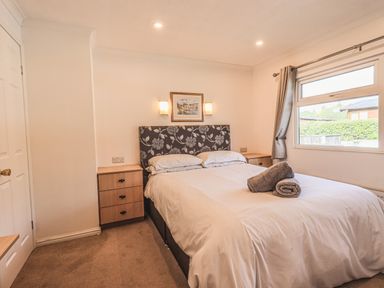 A bedroom with a double bed a floral headboard two bedside tables and a window at Sunny Brow Lodge Lakeside 5 White Cross Bay near Windermere