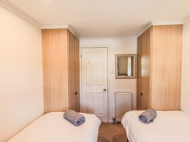 A bedroom with two single beds with towels on them and wooden wardrobes on both sides at Sunny Brow Lodge Lakeside 5 White Cross Bay near Windermere