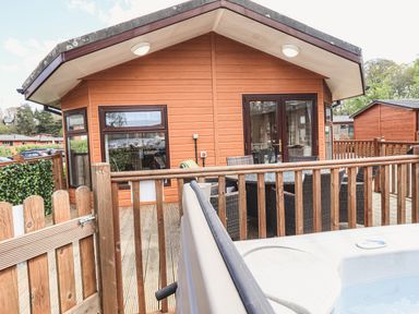 Wooden deck with railing and patio furniture outside a wooden cabin at Sunny Brow Lodge in Lakeside 5 White Cross Bay near Windermere