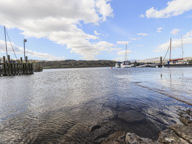 A lakeside view with boats docked at piers and hills in the background at Sunny Brow Lodge Lakeside 5 White Cross Bay near Windermere