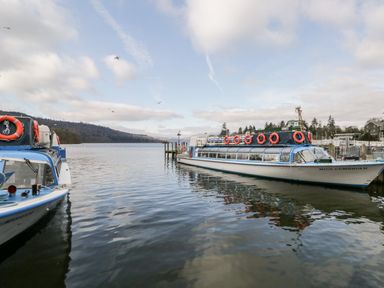 Two boats docked on a lake with hills and trees in the background at Badgers Hollow Lodge Grasmere 30 White Cross Bay near Windermere
