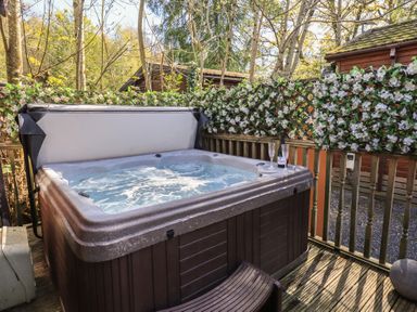 An outdoor hot tub surrounded by flowers at Badgers Hollow Lodge Grasmere 30, White Cross Bay near Windermere
