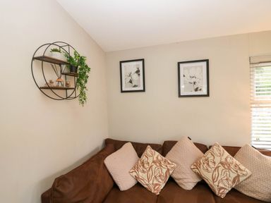 A living room with a sofa and wall art at Badgers Hollow Lodge in Grasmere 30, White Cross Bay near Windermere