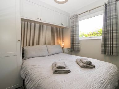 A bedroom with a bed and bedside table at Badgers Hollow Lodge Grasmere 30 White Cross Bay near Windermere