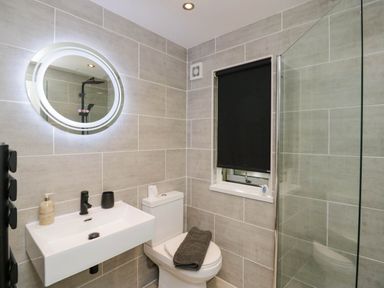 A bathroom with a shower, toilet, sink and mirror at Badgers Hollow Lodge Grasmere 30, White Cross Bay near Windermere