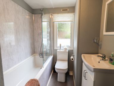 A bathroom with a bathtub shower combination toilet and sink at Pinehaven Lodge Grasmere 6 White Cross Bay near Windermere