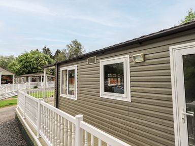 An exterior view of a gray mobile home with white framed windows and a white railing at Pinehaven Lodge Grasmere 6 White Cross Bay near Windermere