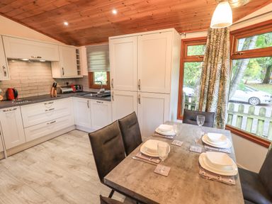 A kitchen and dining area with a set table and large windows at Cedar Lodge Langdale 20 White Cross Bay near Windermere